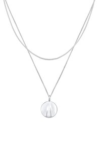 Silverhalsband med två tunna kedjor. Har en rund berlock med en polerad yta som reflekterar ljus och visar mjuka spår.