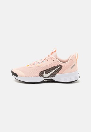 Jasnoróżony but do biegania Nike Trail ATC z białą środkową podeszwą, czarną podeszwą zewnętrzną, białym logo Nike i sznurowanym zapięciem.