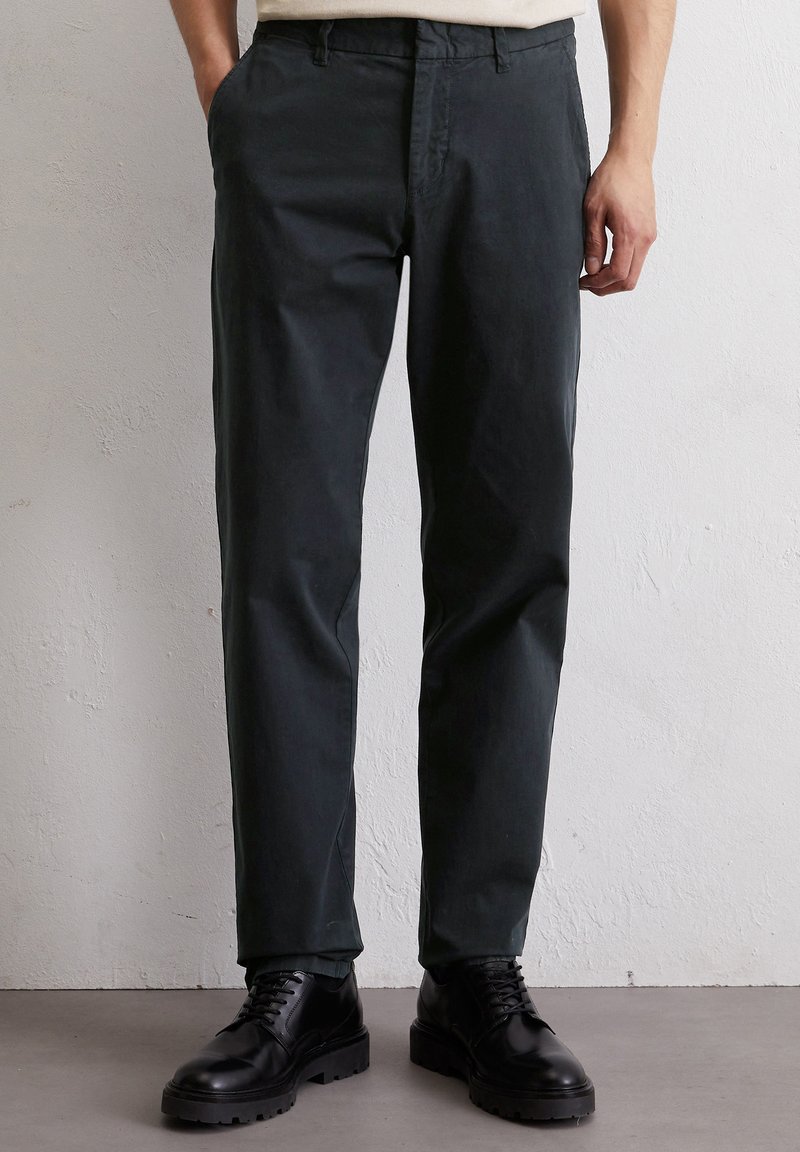 Donkergroene katoenen broek met een rechte pasvorm, voorzien van een klassiek vijf-pocket ontwerp en een knoopsluiting. Gestyled met zwarte veterschoenen.