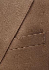 Brauner Stoffdetail mit einer Tasche und sauberer Naht. Die Textur ist glatt und hat ein strukturiertes Aussehen, geeignet für formelle Kleidung.