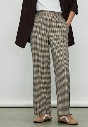 Braun-weiße Karottenhose mit hohem Bund und geradem Schnitt, ausgestattet mit Seitentaschen und minimalistischem Design. Weicher Stoff.