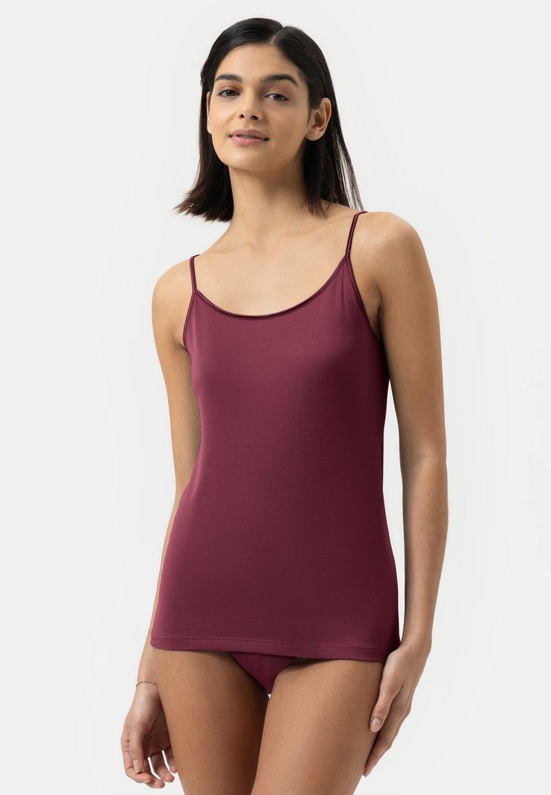 Bordowa koszulka na cienkich ramiączkach, gładka w fakturze i dopasowana. Materiał jest elastyczny i lekki, odpowiedni do noszenia na cebulkę lub na co dzień.