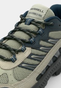Jasnoszare i granatowe buty trekkingowe z siateczkowym wierzchem, teksturowanymi overlays i wzorzystymi sznurowadłami. Posiadają trwałą gumową podeszwę oraz wyściełany język.
