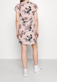Floral dress in soft pink fabric with short sleeves, featuring green and maroon leaves and birds, knee-length cut with a relaxed fit.