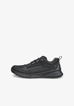 Scarpa da trekking bassa nera con suola texturizzata, frontale con lacci, linguetta al tallone e colletto imbottito, mostrata di profilo su sfondo bianco.