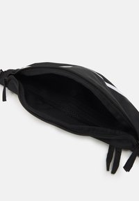 Svart dragkedjefodral med en texturerad insida och meshnätficka. Har en slät tygutsida och dubbla dragkedjehandtag.