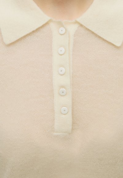 Pull en tricot couleur crème avec col et cinq boutons assortis sur la patte de boutonnage devant.