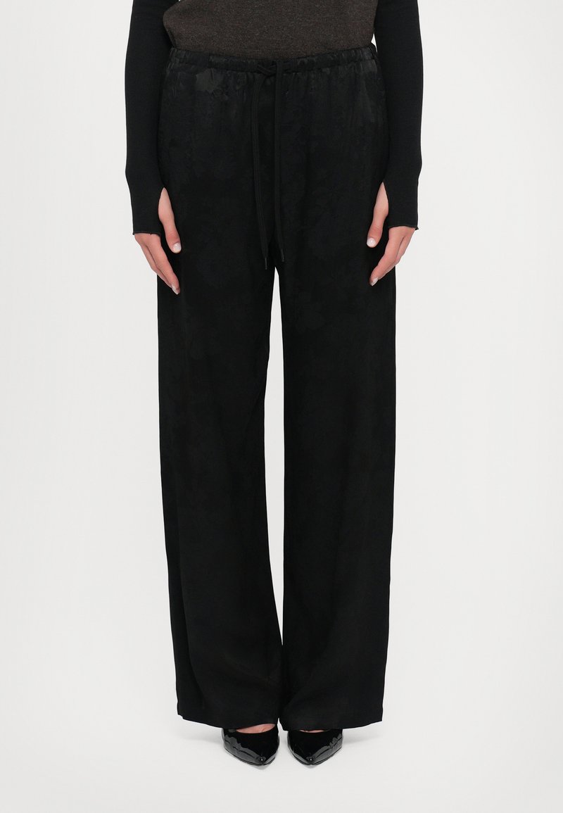 Black wide-leg trousers with a subtle floral pattern, elastic waistband with drawstring, made from a smooth, lightweight fabric.