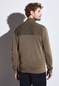 Knit sweater in earthy olive with ribbed texture, features a patterned yoke; high collar and long sleeves complete the design.
