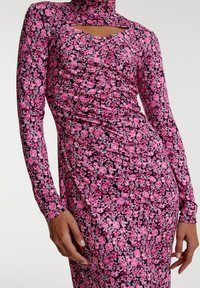 Blumenkleid mit langen Ärmeln, hochgeschlossen und mit ausgeschnittenem Detail. Hergestellt aus elastischem Stoff, mit pinken Rosen auf einem dunklen Hintergrund.