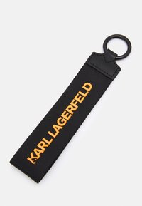 Schwarzer Stoff-Schlüsselanhänger mit strukturiertem Finish, versehen mit "KARL LAGERFELD" in kräftiger orangefarbener Schrift und einem runden Metallbefestigungsring.