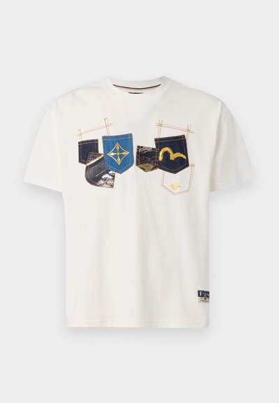 T-shirt en coton blanc avec un design graphique de diverses poches en denim avec des accents bleu, noir et jaune, à manches courtes et col rond.
