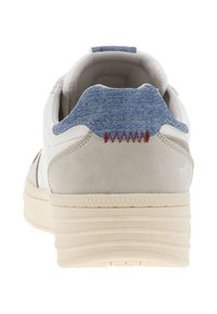 Sneaker bianca con corpo in suede beige e linguetta blu denim, caratterizzata da cuciture rosse e suola testurizzata per una migliore aderenza.