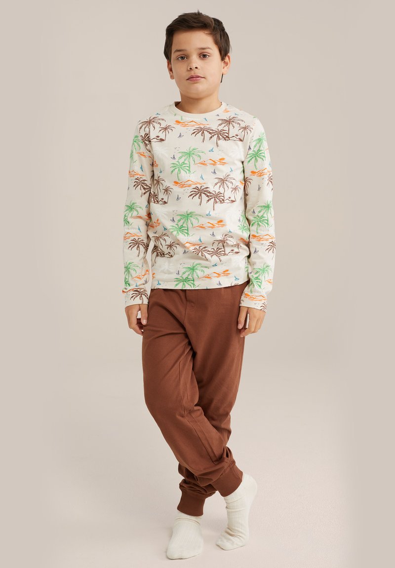 Långärmad pyjamaströja i crème med grön palm- och orange solnedgångsmönster, tillsammans med bruna långbyxor. Mjuk bomullsmaterial, avslappnad passform.