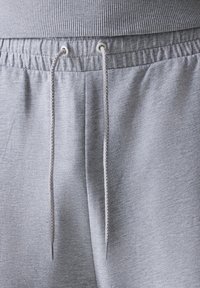Šedé jogger nohavice s textúrovanou textíliou, s elastickým pásom, sťahovacou šnúrkou a bočnými vreckami.