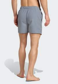 Modré a biele pruhované plavky s elastickým pásom a bočnými vreckami. Tkanina vyzerá ľahká a má jemnú textúru.