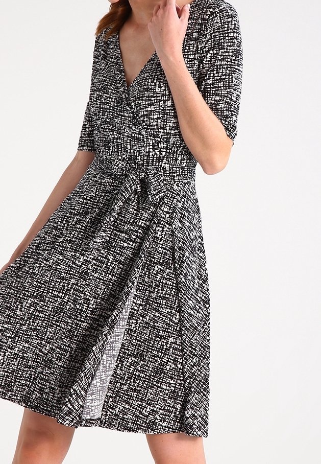 Svart-och-vit omlottklänning med korta ärmar, texturerad tyg med en geometrisk mönster och en åtsittande midja med en utsvängd kjol.