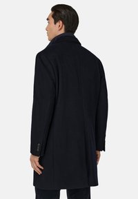 Tumesinine villane mantel, millel on lõige krae, selja lõhik ja nupuga mansetid. Omab sujuvat tekstuuri ja kohandatud istuvust.