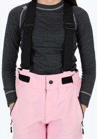 Rosa snöbyxor med justerbara svarta hängslen, kontrasterande svart midja, sidofickor med dragkedja och en smidig yta.