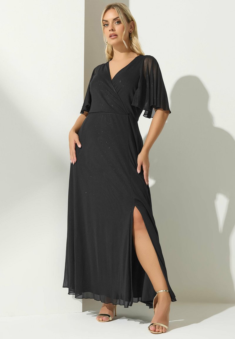 Vestido maxi negro con mangas flotantes, escote en V pronunciado, abertura lateral y un sutil brillo. La tela ligera fluye elegantemente hasta el suelo.