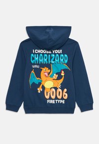 Jūras zila kapuce ar Charizard grafiku, uzdrīkstinošu tekstu "ES IZVĒLOS TEVI!" un "UGUNS TIPS", ar oranžām, tirkīza un baltām krāsām. Kokvilnas maisījuma materiāls.