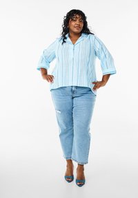 Lysblåstribet skjorte med krave og trekvartærmer, parret med lysblå ripped jeans og blå åbne hæle.