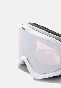 Weiße Skibrille mit einer gewölbten, transparenten Linse, dunkler Schaumstoffpolsterung oben und einem Logo an der Seite. Abgerundete Kanten und strukturierte Details.