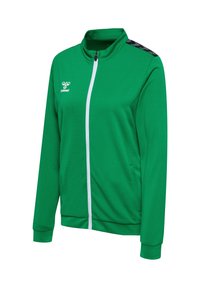 Veste de sport verte à manches longues avec fermeture éclair blanche sur le devant, motif noir sur les épaules et petit logo blanc sur la poitrine gauche.