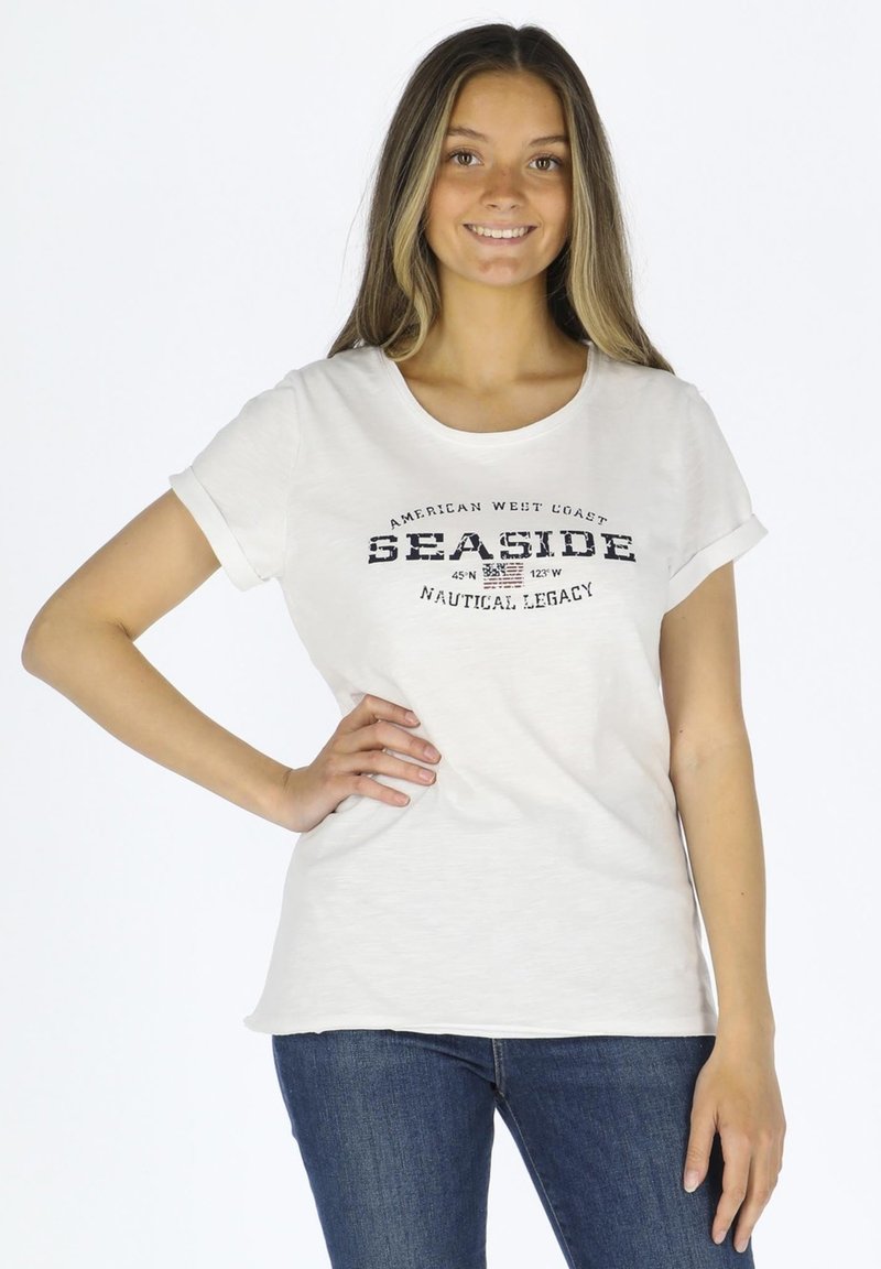 Witte katoenen T-shirt met opgerolde korte mouwen, voorzien van een geprinte "SEASIDE" graphic in marineblauw, en een relaxte pasvorm, gecombineerd met blauwe jeans.