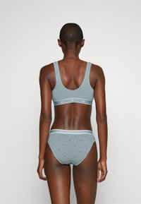 Gaiši zils sporta krūšturis un atbilstoši apakšbikses ar Lacoste logo rakstu. Mīksts audums, elastīgas lentes un cieša piegriezte. Aizmugures skats atspoguļo dizaina detaļas.