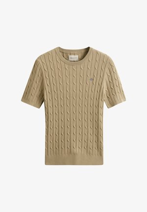 Beige kabelgebreide trui met korte mouwen, ronde hals en een klein geborduurd logo op de linkerborst.