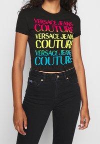 Svart kortärmad T-shirt med flerfärgad "VERSACE JEANS COUTURE"-logotyp i rosa, gult och blått. Mjuk tyg med en figursydd design.