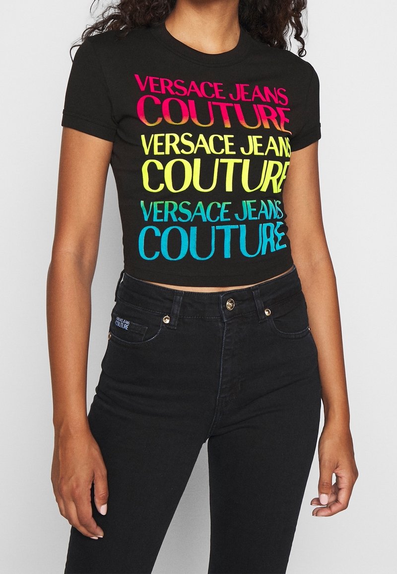 Svart kortärmad T-shirt med flerfärgad "VERSACE JEANS COUTURE"-logotyp i rosa, gult och blått. Mjuk tyg med en figursydd design.