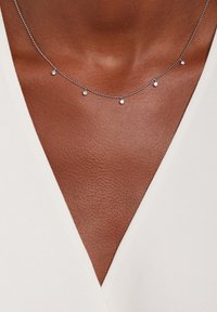 Zilveren ketting met kleine, gelijkmatig verdeelde ronde kralen. Heeft een fijn, delicaat ontwerp. Draagt tegen een V-halstop op de huid.