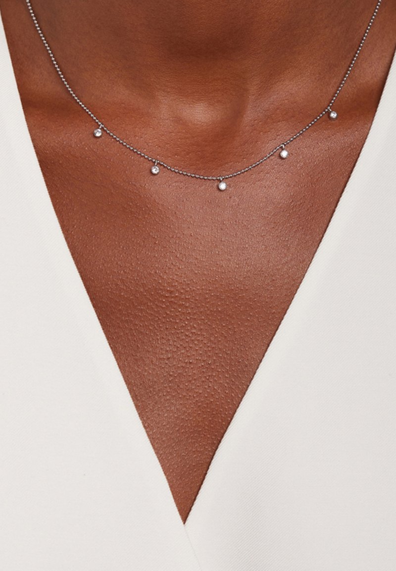 Zilveren ketting met kleine, gelijkmatig verdeelde ronde kralen. Heeft een fijn, delicaat ontwerp. Draagt tegen een V-halstop op de huid.