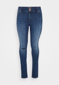 Jeans skinny de tiro alto en azul oscuro con tres botones frontales y un detalle de rasguño en la rodilla derecha, sobre un fondo claro.