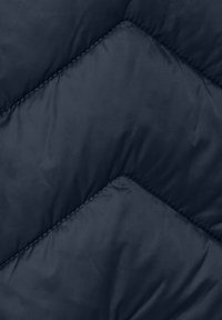 Tissu bleu marine matelassé avec un motif en chevron, présentant une texture lisse et des détails de couture contrastants.
