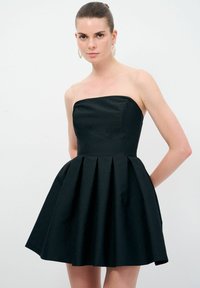 Svart avtagbar klänning med en figursydd livdel och en utsvängd veckad kjol, tillverkad av textil. Enkel design och enfärgad.