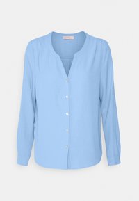 Chemise bleu clair à manches longues, au col rond et en tissu texturé. Présente cinq boutons sur le devant et un drapé doux.