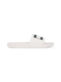 Bela drsna sandal z širokim trakom, ki ima kontrastni črni pravokotnik in črke. Gladek zaključek, pravokotna podplat, minimalističen dizajn.