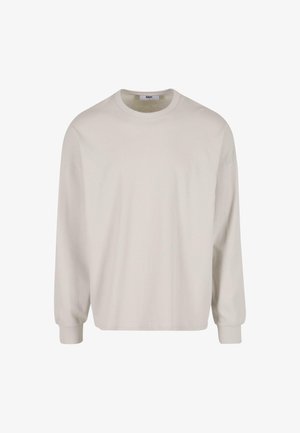 Világos bézs színű, hosszú ujjú pamut póló, kerek nyakkivágással és bordázott mandzsettával, laza szabással és sima textúrával.