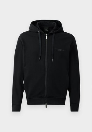 Schwarze Zip-Hoodie aus weichem Material, mit Kapuze, Kordelzügen und geprägtem Logodetail auf der Brust. Schmaler Schnitt mit gerippten Bündchen.