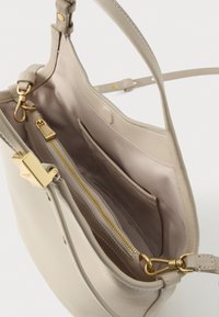 Beige læderhåndtaske med åbent topstykke, guldfarvet hardware, lynlåslomme indvendigt og glat tekstur. Har justerbar skulderrem.