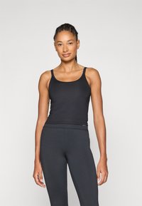 Svart tettsittende singlet med tynne stropper, laget av glatt stoff. Designet har en scoop-hals og en slank silhuett.