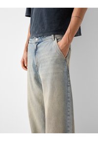 Ljusblå denimjeans med avslappnad passform, som har en knapp- och dragkedjeförslutning, fem fickor och en urtvättad struktur.