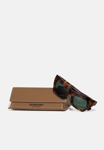 Burberry saulesbrilles ar bruņurupuču raksta rāmjiem un zaļiem stikliem, kopā ar brūnu mākslīgās ādas maciņu, uz kura ir iegriezts "Burberry".