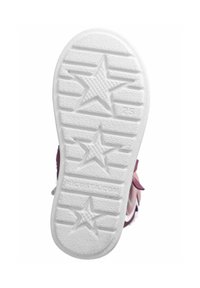 Suela de zapato de goma blanca con patrones de estrellas y ranuras horizontales. Presenta una textura suave. Parte de la parte superior morada es visible en el borde.
