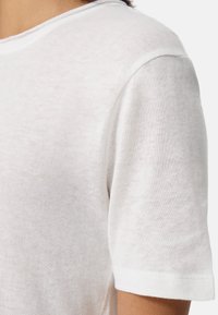 Witte shirt met korte mouwen, gemaakt van een zachte, lichtgewicht stof met een iets doorschijnende textuur en een ronde hals. Eenvoudig en minimalistisch ontwerp.