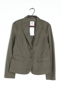 Blazer da donna verde oliva con colletto a risvolto, due bottoni, tasche anteriori a patta, appeso a un gancio nero su sfondo bianco.