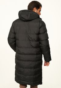 Langer schwarzer Steppmantel mit Kapuze, der gesteppten Bereiche, eine glatte Textur und einen Reißverschluss am unteren Ende aufweist. Einfaches und funktionales Design.